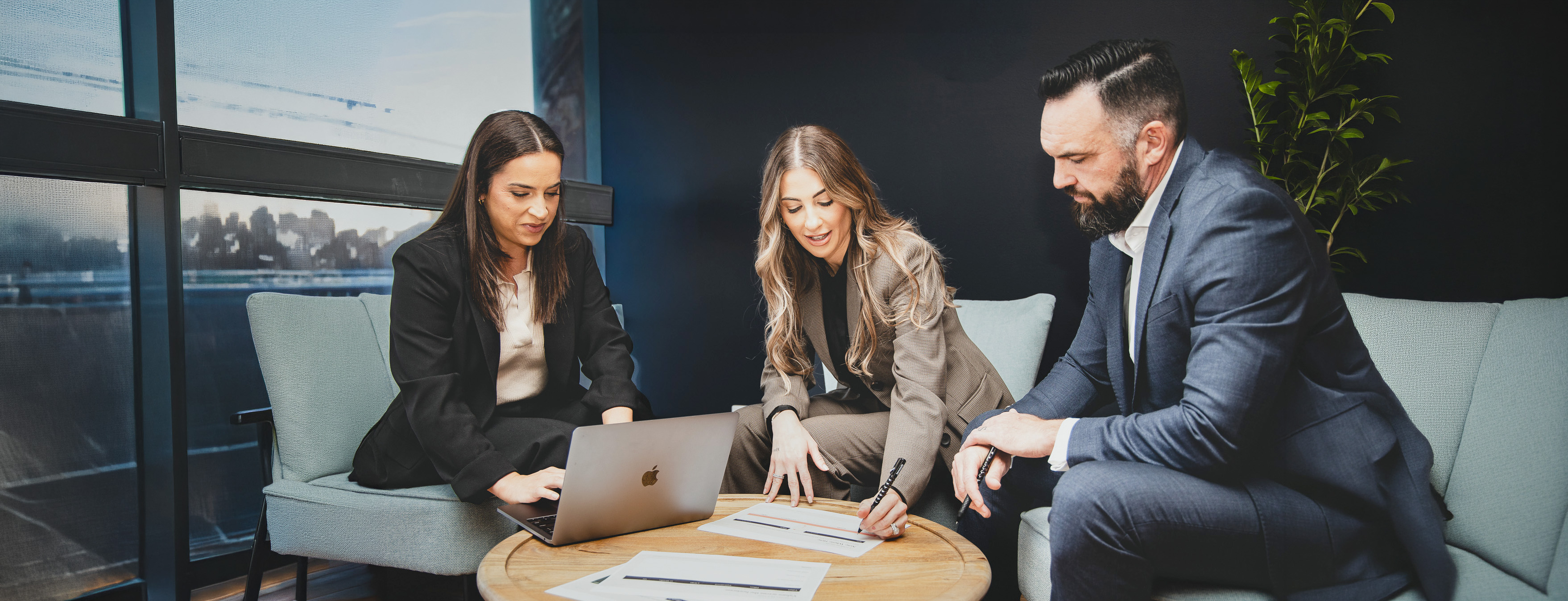 Three colleagues reviewing documents together at a coffee table